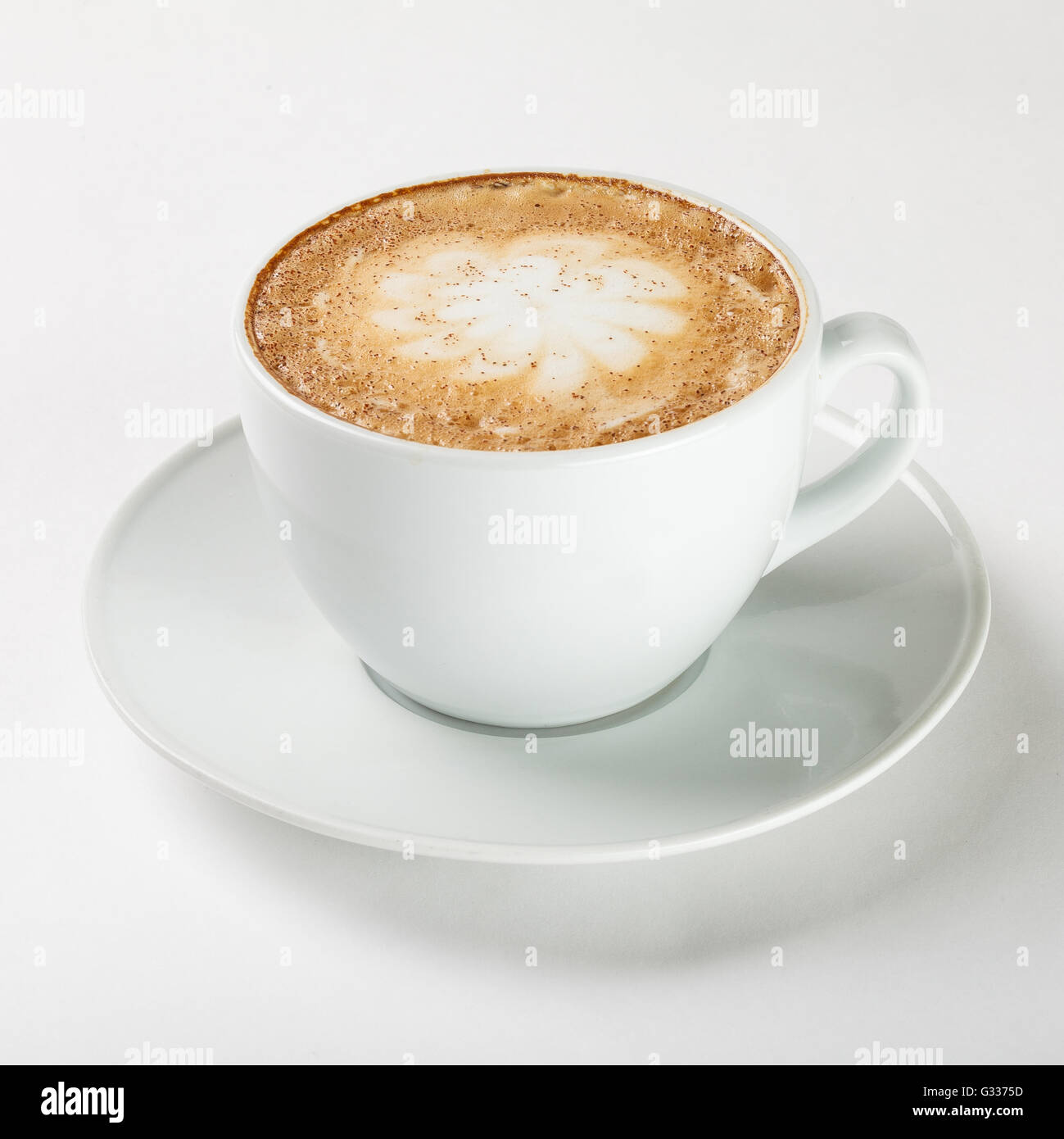 Leckeren Cappuccino in einer weißen Tasse auf dem Teller auf weißem Hintergrund. Schließen Sie die Seitenansicht. Stockfoto