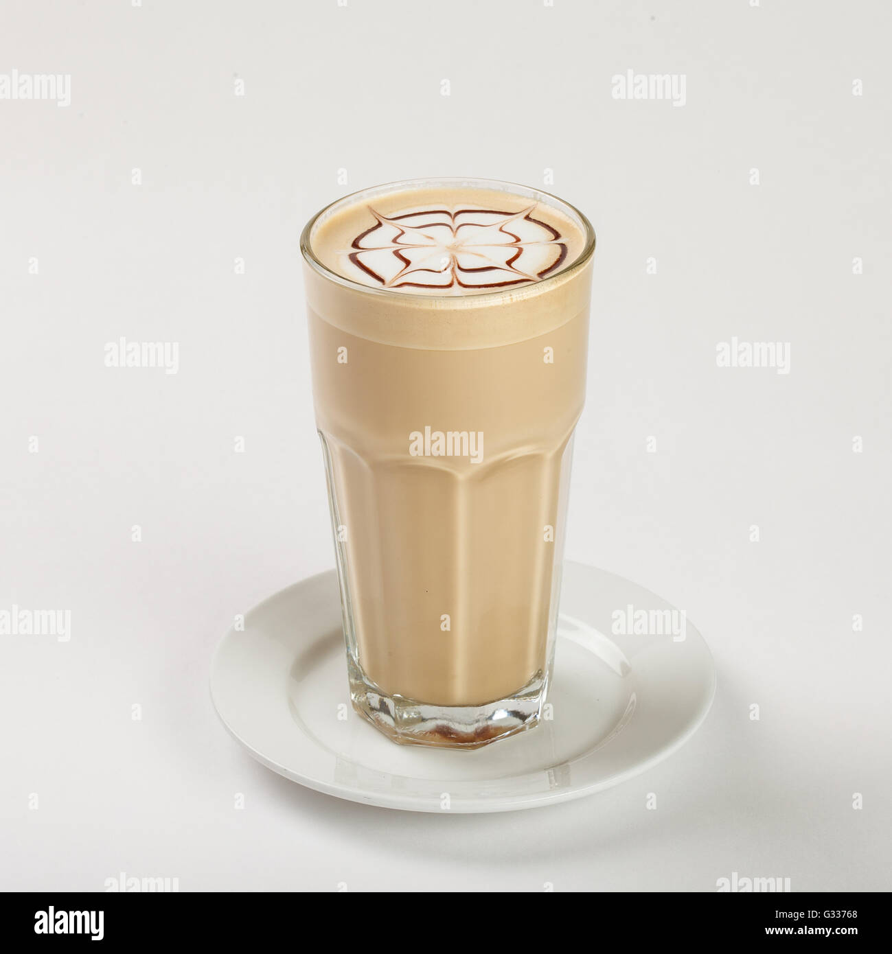 Leckeren Latte in ein hohes Glas auf dem Teller auf weißem Hintergrund. Schließen Sie die Seitenansicht. Stockfoto