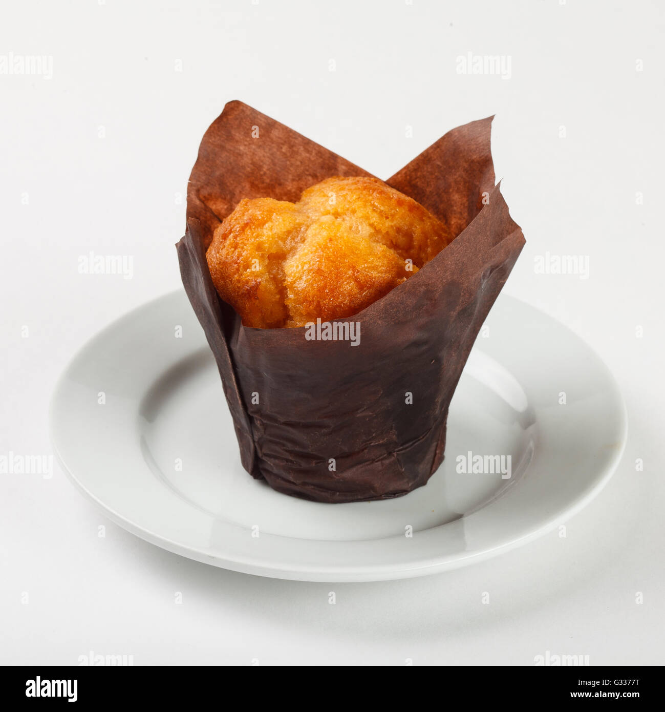 Leckere Muffin Kuchen in braunem Papier auf die Platte auf weißem Hintergrund. Schließen Sie die Seitenansicht. Stockfoto
