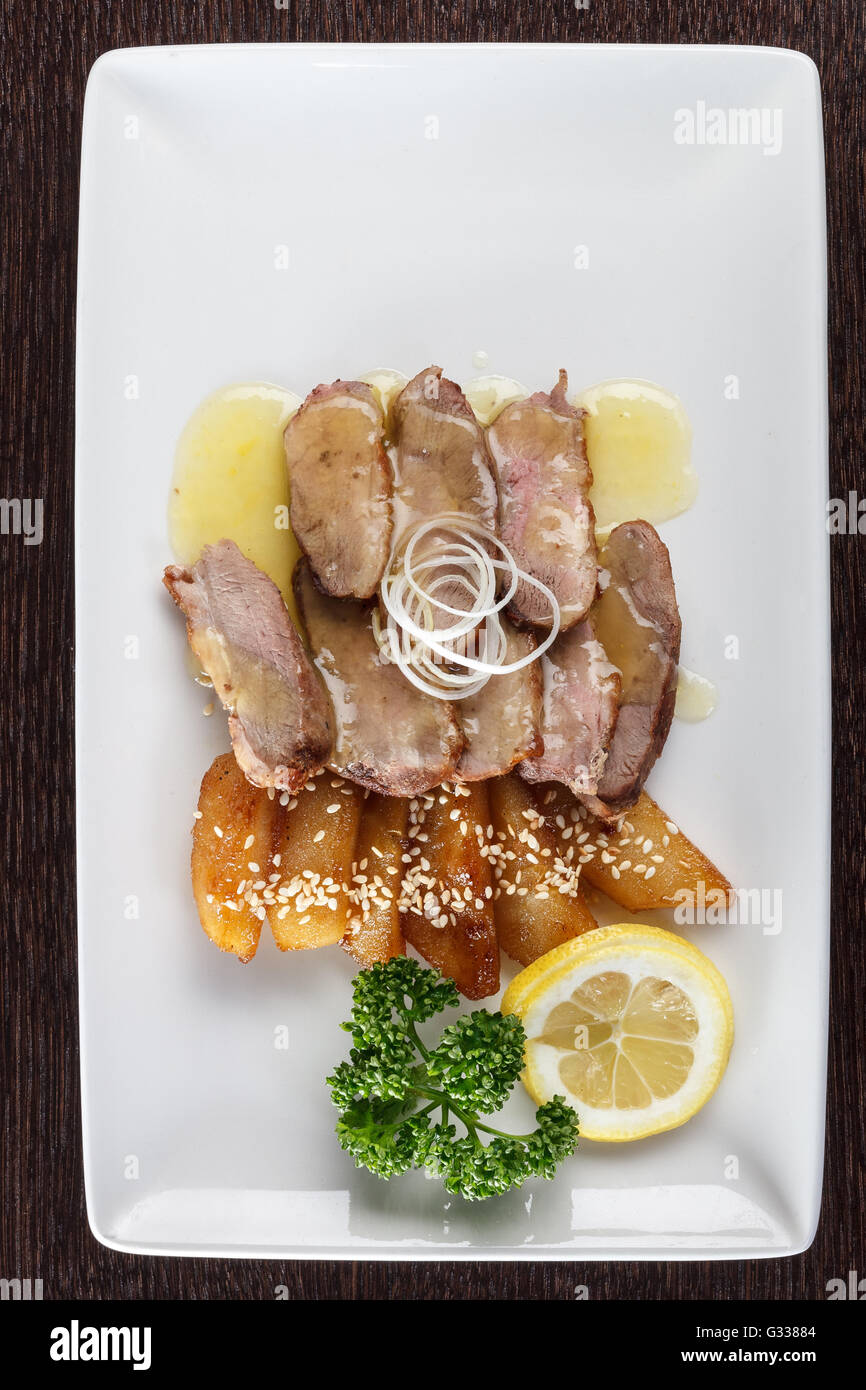 Fleischstücke zartes Kalbfleisch mit Soße, Bratkartoffeln und einer Scheibe Zitrone und Petersilie auf weißen Teller. Europäische Küche. Top vie Stockfoto