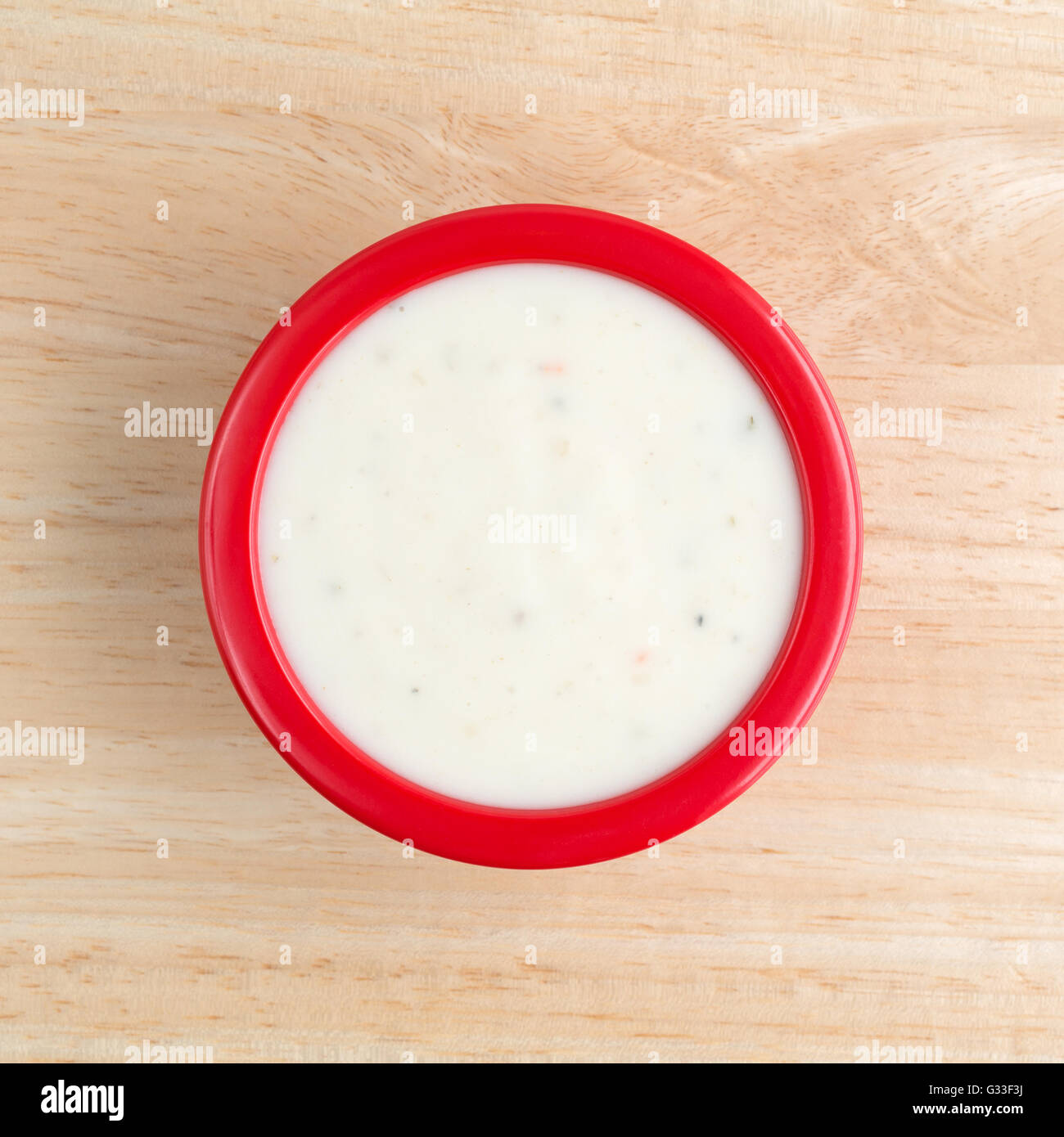 Draufsicht auf eine kleine rote Schüssel cremig italienischer Salat-Dressing auf einem Holztisch. Stockfoto