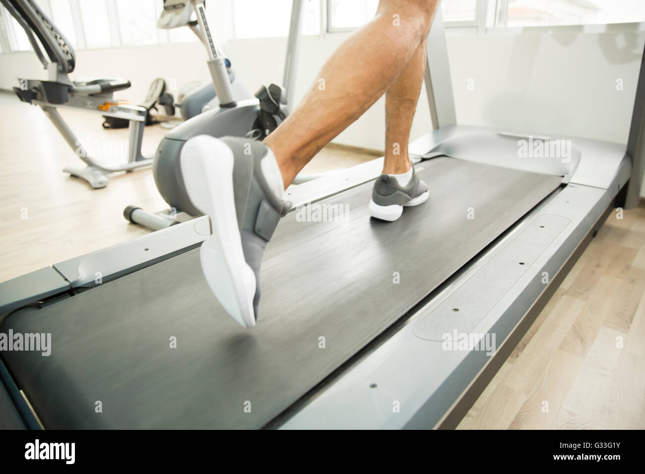 Nahaufnahme der männlichen Beine auf einem Laufband im Fitnessstudio Stockfoto
