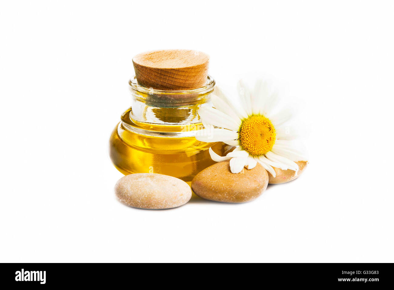 Kamillenöl für Spa-Behandlung mit Blumen- und Massage Steinen isoliert Stockfoto