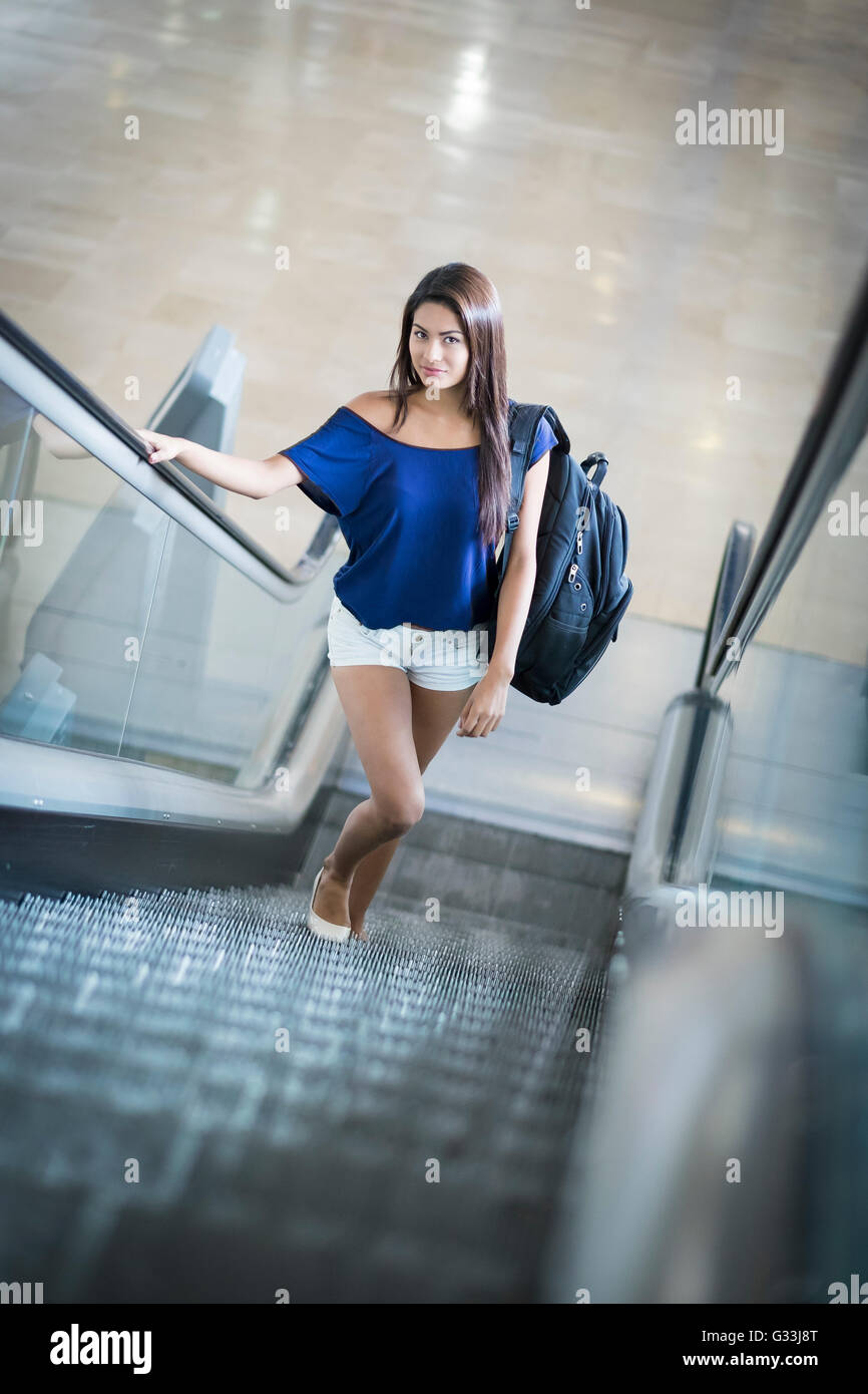 Junge schöne Frau mit Rucksack auf einer Rolltreppe hinauf Stockfoto