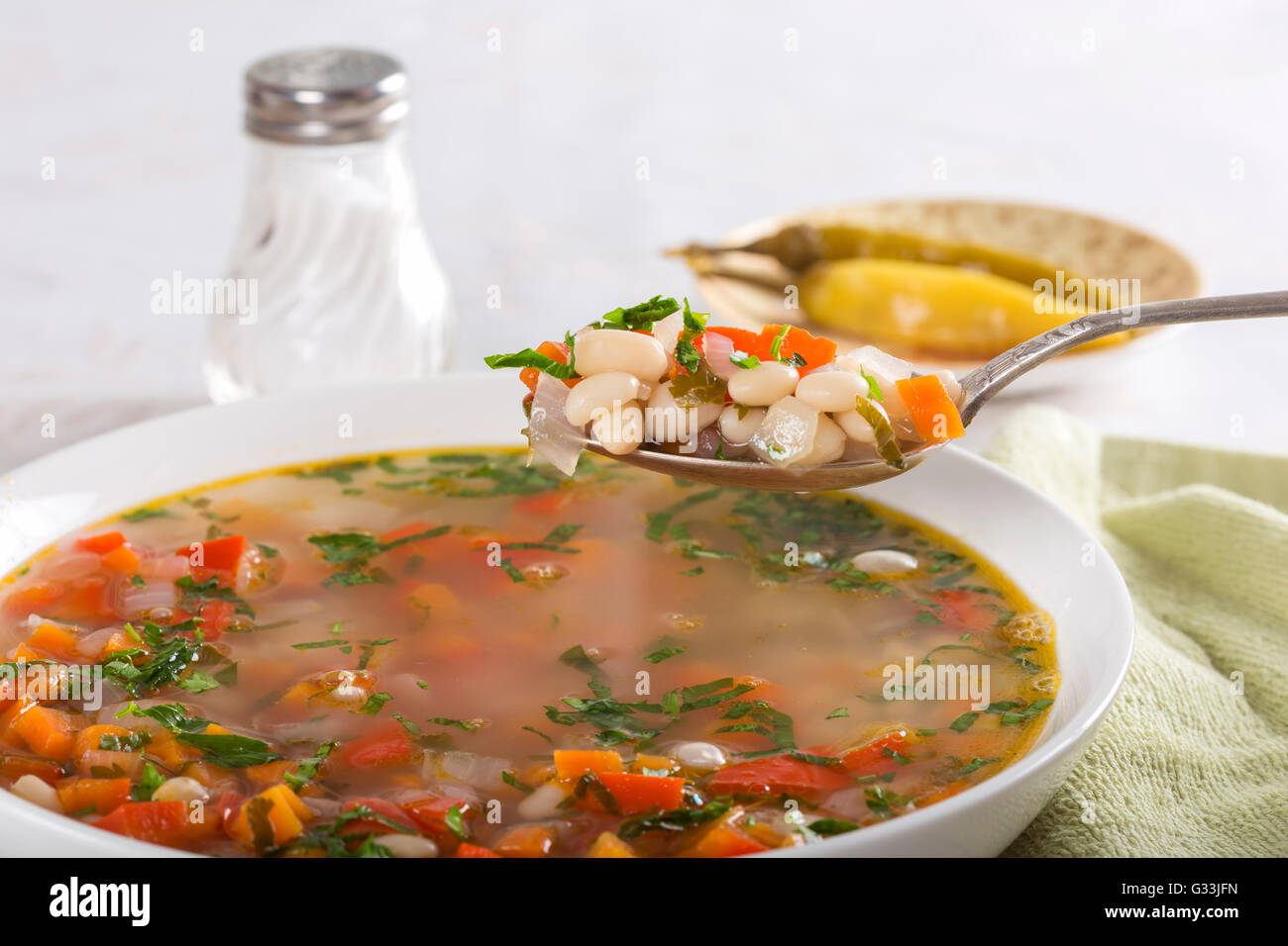 Bohnensuppe mit Gemüse in einer weißen Schüssel auf Tisch Stockfoto