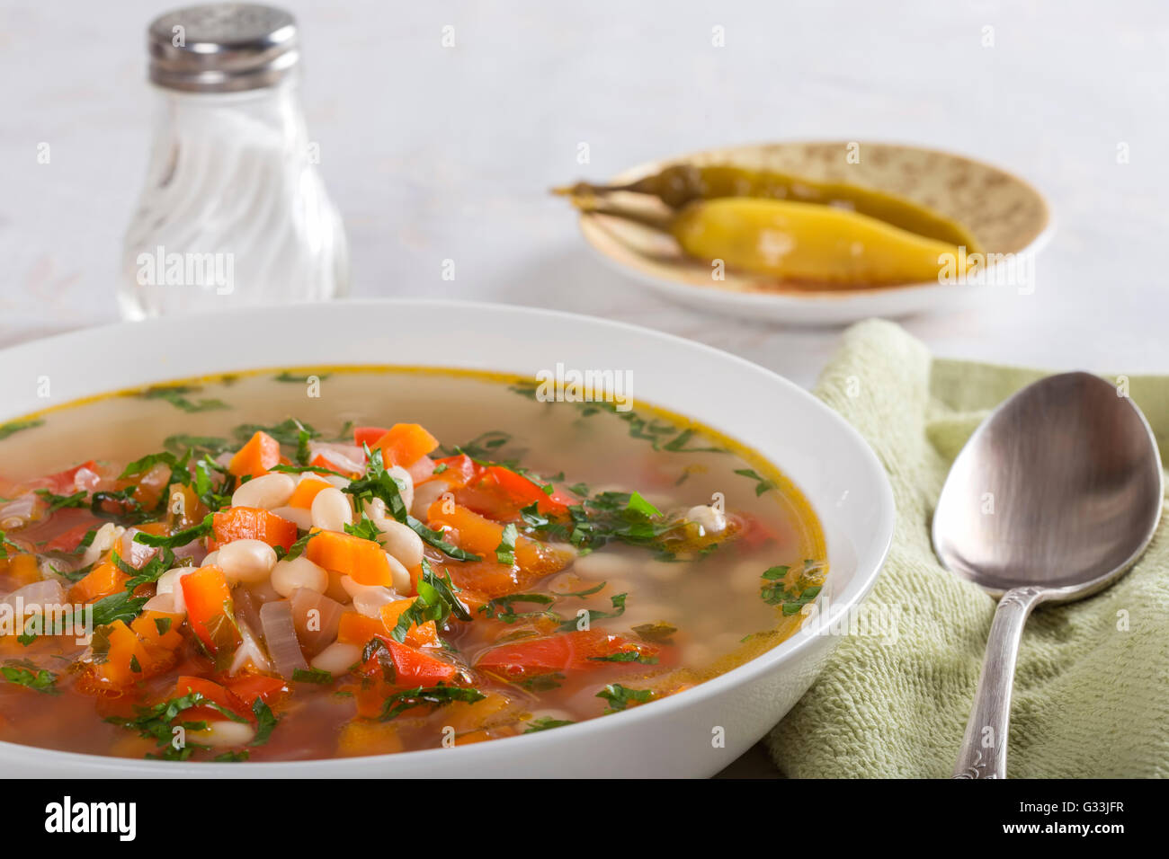 Bohnensuppe mit Gemüse in einer weißen Schüssel auf Tisch Stockfoto