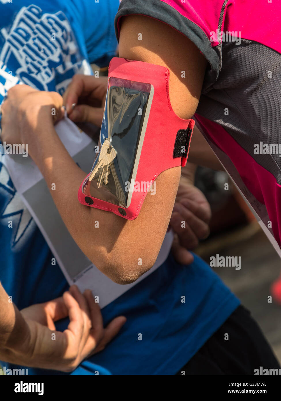 Mädchen mit Smartphone-Armbinde-Kasten befestigen Sie die Startnummer t-Shirt vor-City-Marathon Stockfoto