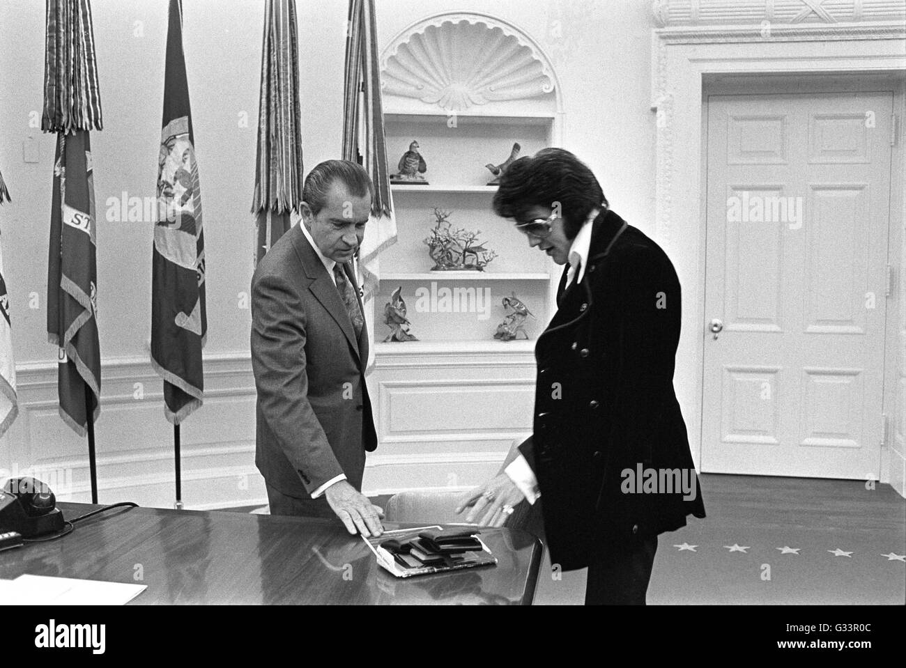 Elvis Presley präsentiert ein signiertes Foto US Präsident Richard M. Nixon im Oval Office im Weißen Haus 21. Dezember 1970 in Washington, DC. Das Treffen wurde von Presley, initiiert, Nixon schrieb einen sechs-seitigen Brief mit der Bitte eines Besuchs mit dem Präsidenten und darauf hindeutet, das er ein "Federal Agent-at-Large" im Bureau of Narcotics und gefährlichen Drogen gemacht werden. Stockfoto