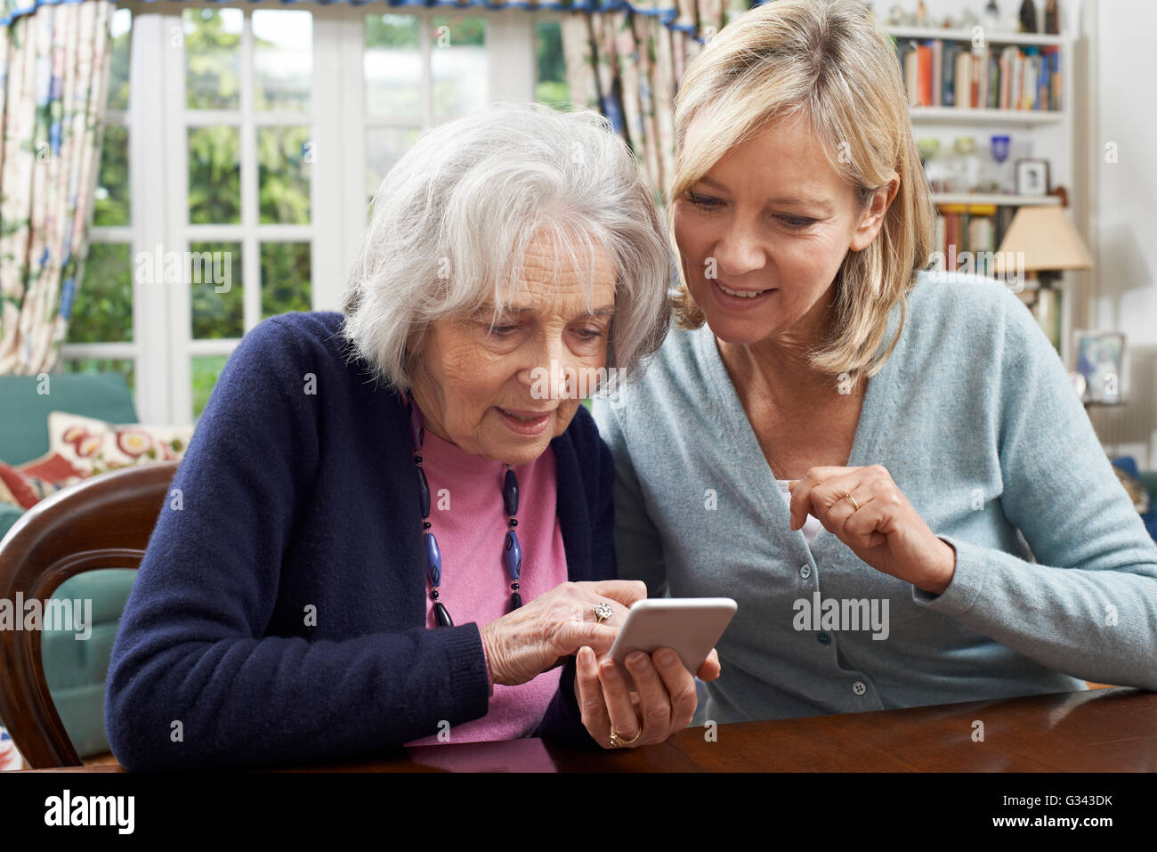 Frau helfen Senior Nachbar zum Mobil telefonieren Stockfoto