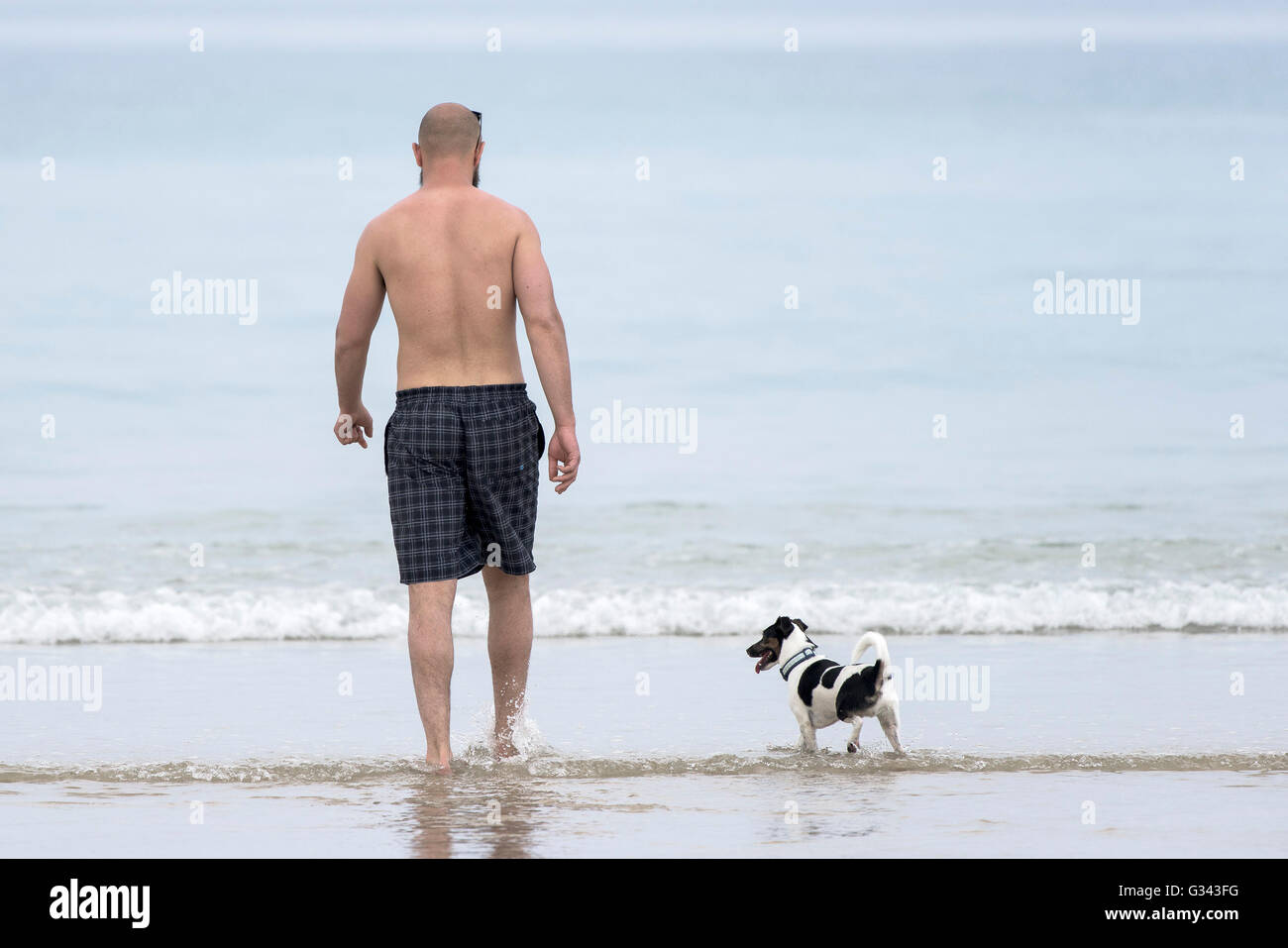 Ein Urlauber und seinem Hund auf Fistral Beach in Newquay, Cornwall. Stockfoto