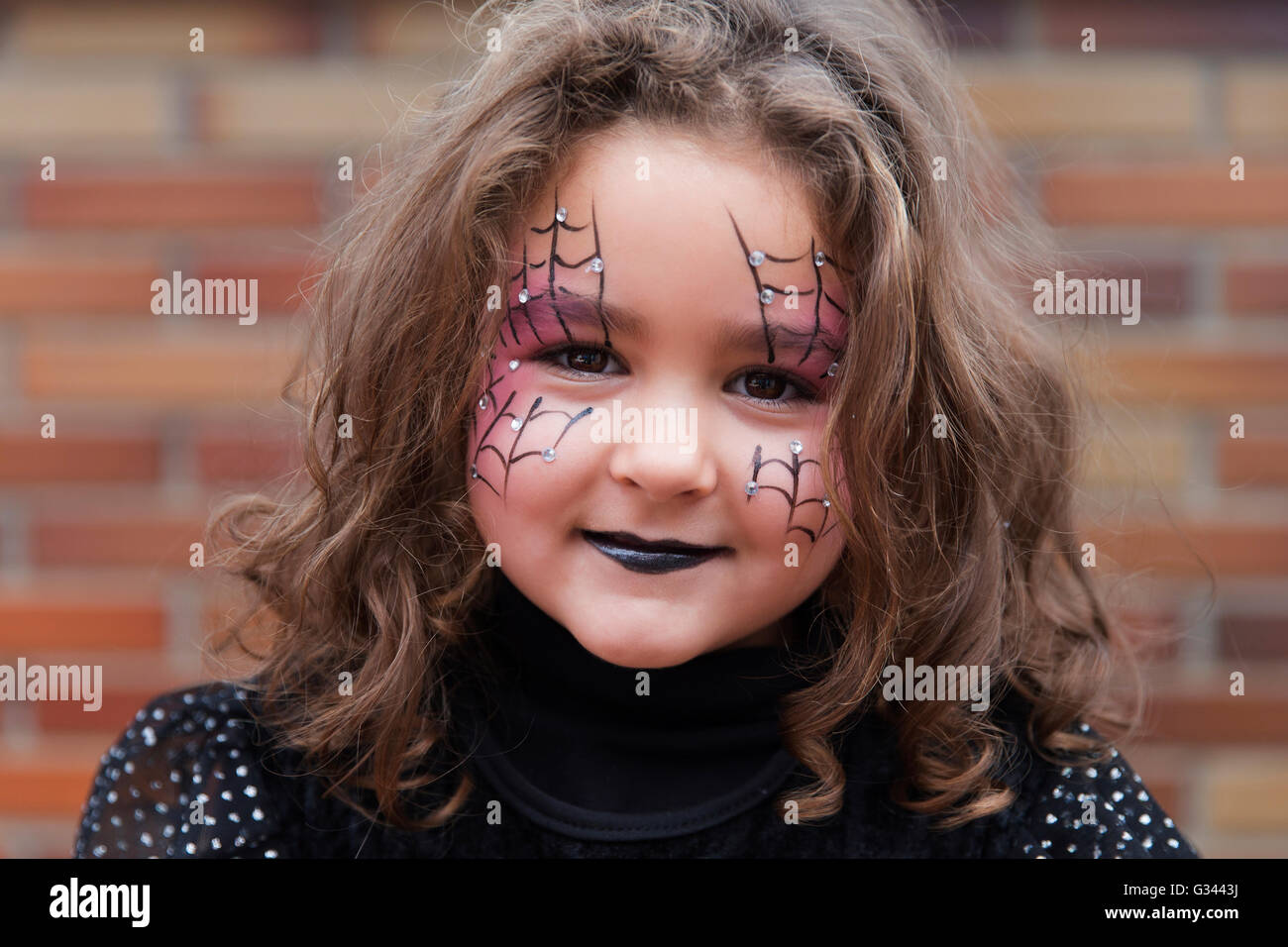 Kleines Mädchen mit Spinnennetz gemalt auf Gesicht, Blick in die Kamera. Halloween Stockfoto