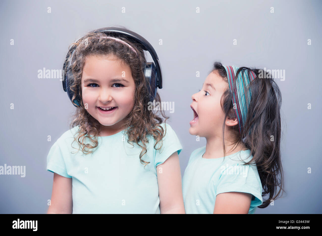 Porträt von kleinen Mädchen schreien an ihrer ältesten Schwester anhören von Musik im Kopfhörer Stockfoto