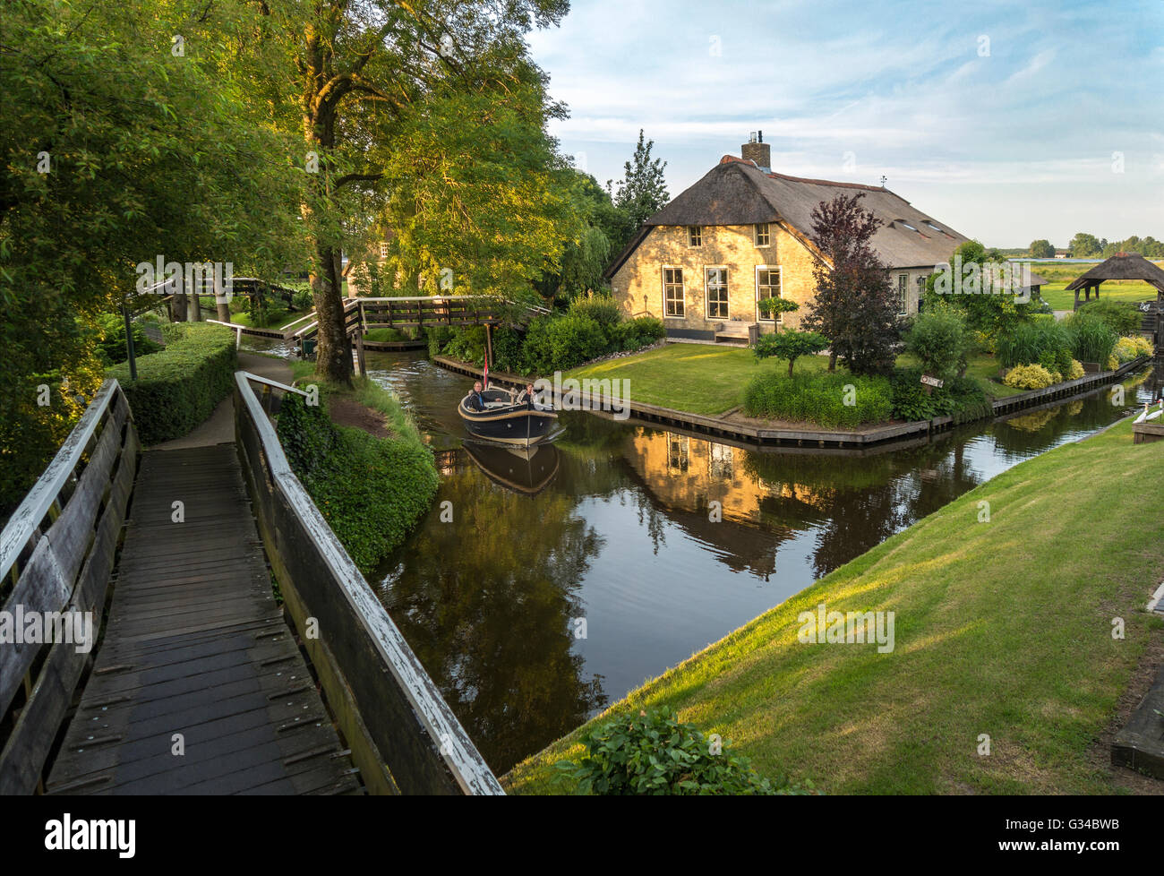 Giethoorn, Niederlande. Boot im Dorpsgracht oder im Dorf Kanal mit umgebauten Bauernhaus auf Insel mit privaten Brücke. Stockfoto