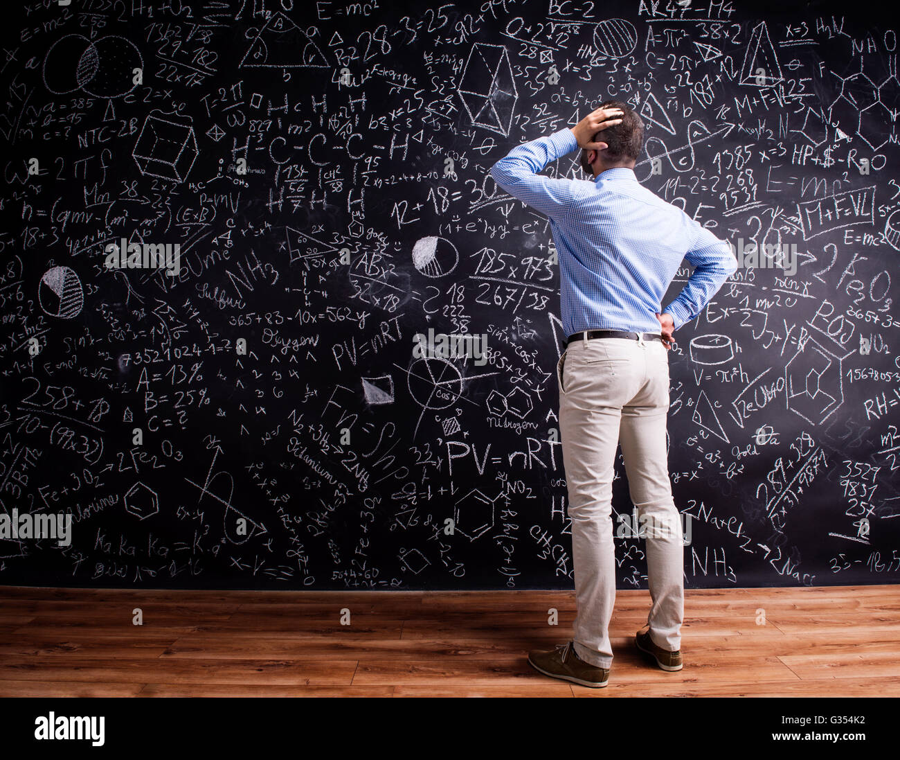 Hipster Lehrer gegen große Tafel mit mathematischen Symbolen Stockfoto