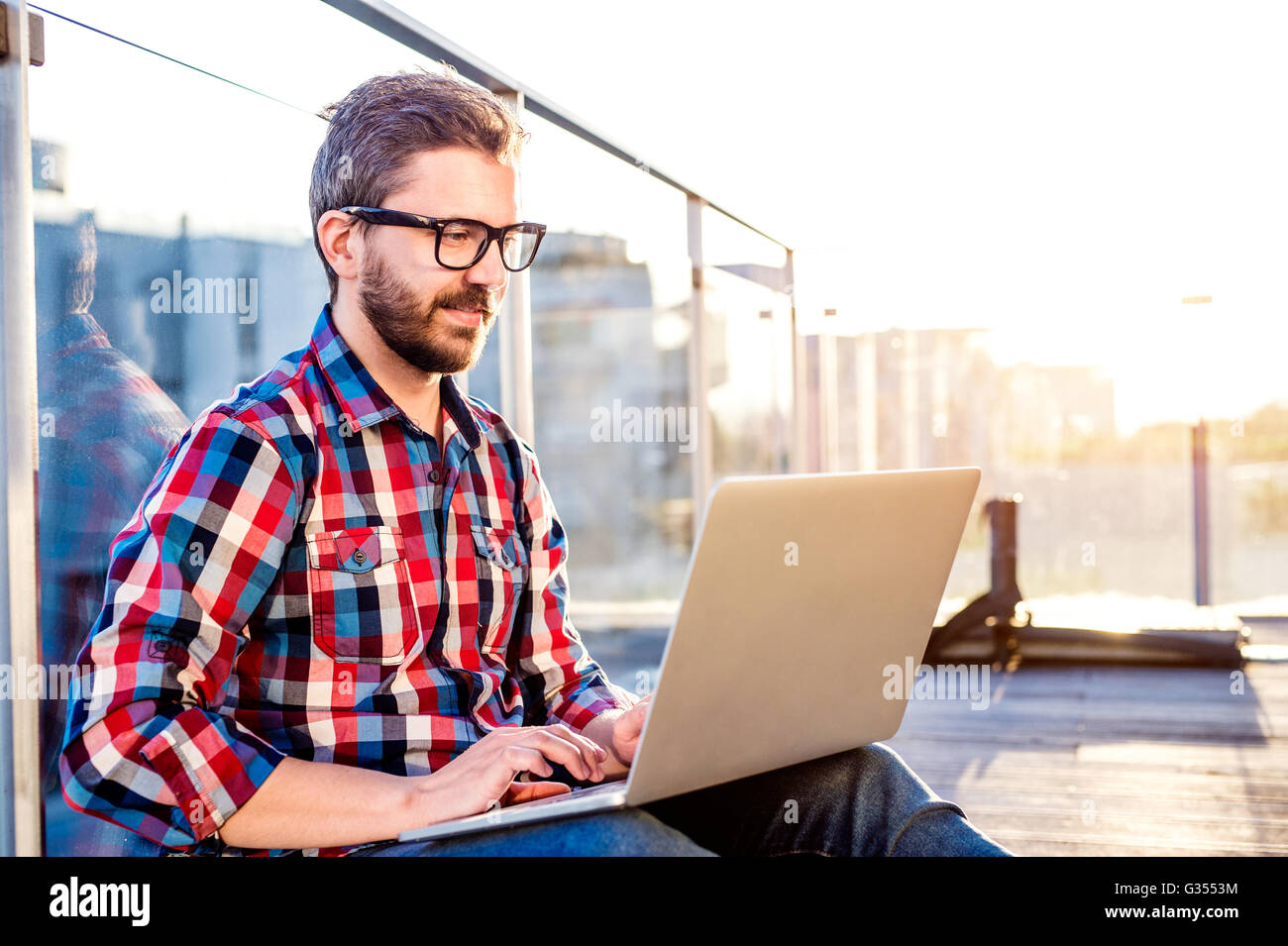 Geschäftsmann, arbeiten von zu Hause am Laptop, am Balkon sitzen Stockfoto