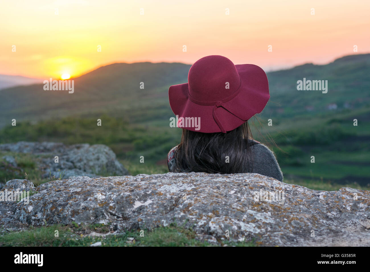 Weibliche Wanderer Sonnenuntergang auf einem Felsen sitzend Stockfoto