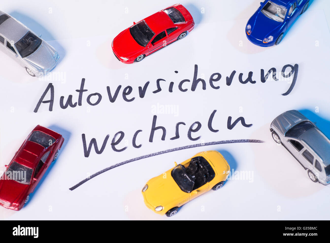 Schriftzug "Kfz-Versicherung wechseln" umgeben von Miniatur-Auto Stockfoto