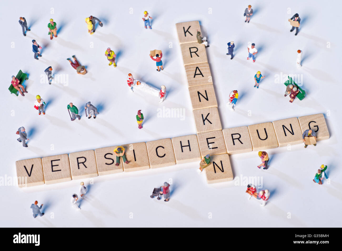 Hölzerne Blöcke mit Buchstaben bilden das Wort Krankenversicherung und sind umgeben von Modellfiguren. Stockfoto