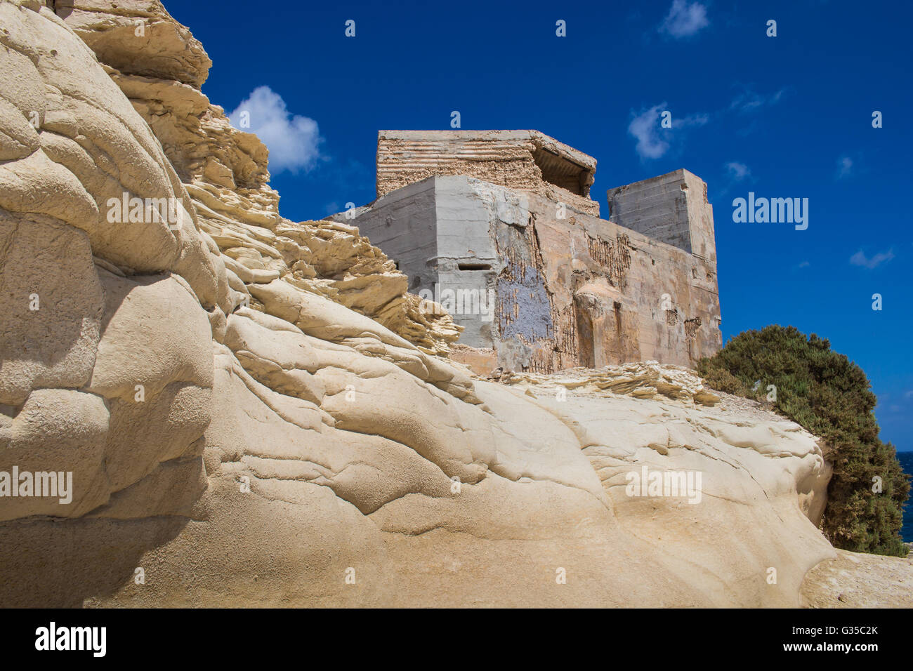 Sand Farbe der Felsen an der Küste des Mittelmeeres, Stadt Marsaskala, Insel Malta. Gebäude auf dem Hügel. Brigh Stockfoto