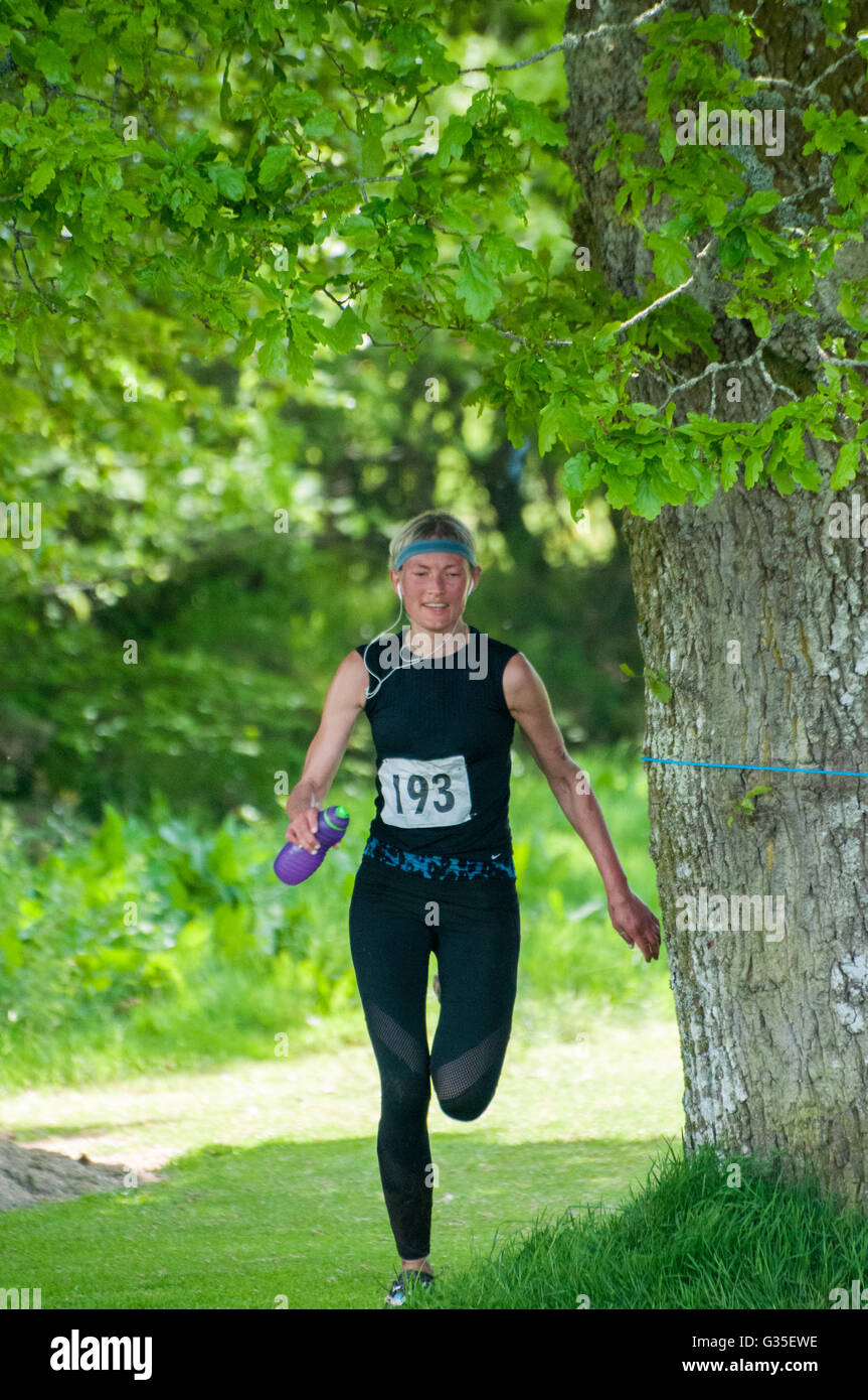 Junge Frau (Erwachsene) Läufer Unterquerung Eiche in dunkler Kleidung mit Trinkflasche und Kopfhörer (keine 193) Stockfoto
