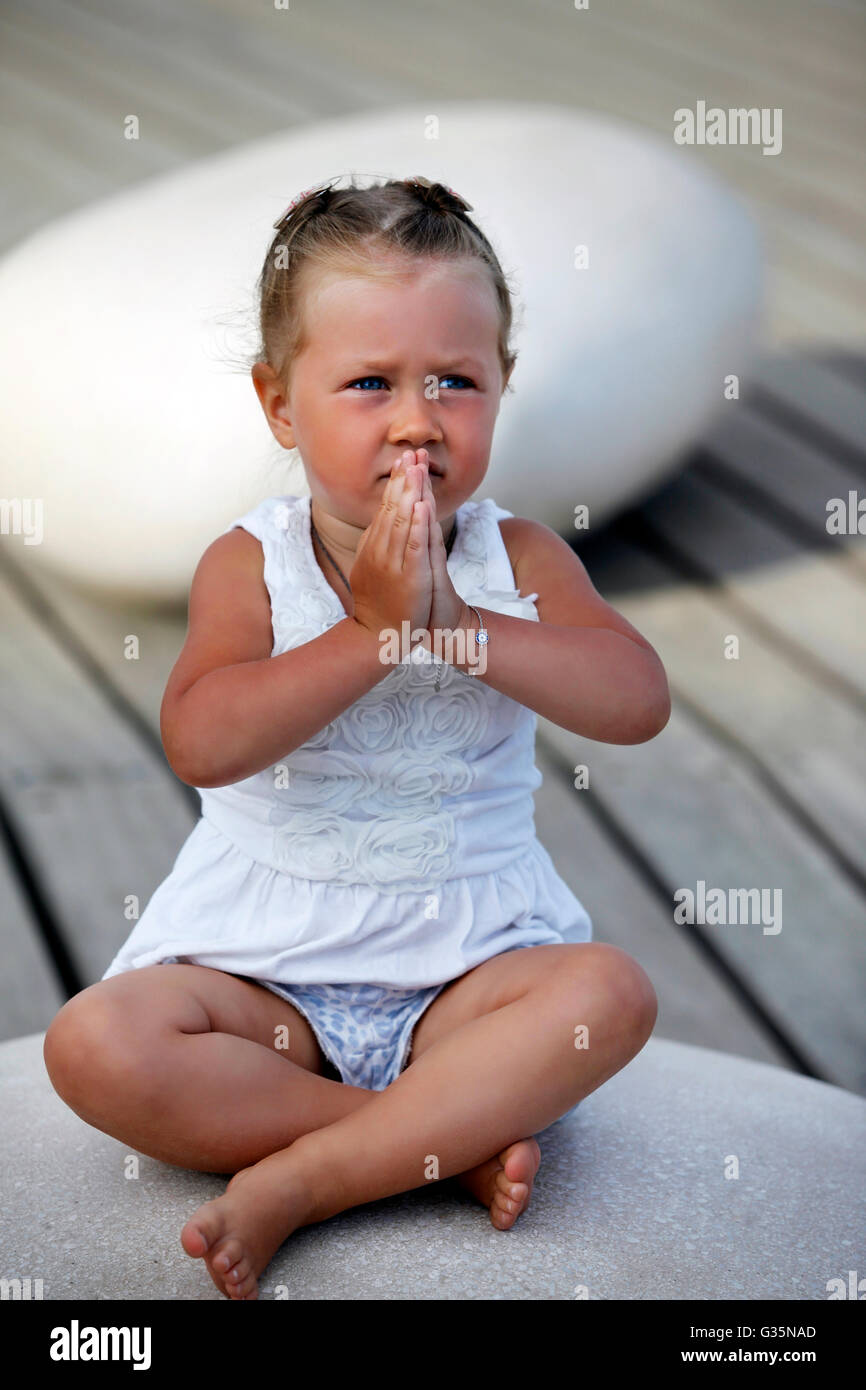 Entzückende kleine Mädchen tun Yoga auf dem großen Stein sitzend Stockfoto