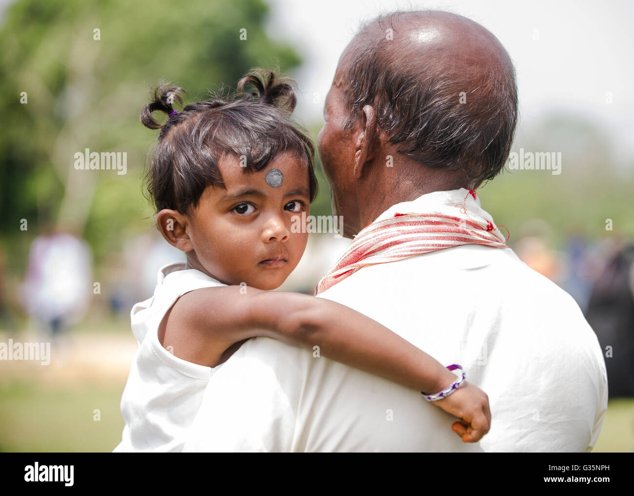 Ein junges Mädchen wird von einem Verwandten in Pan Bari Village im Kaziranga Nationalpark in Indien am 13. April 2016 statt.  Bildnachweis: Stockfoto