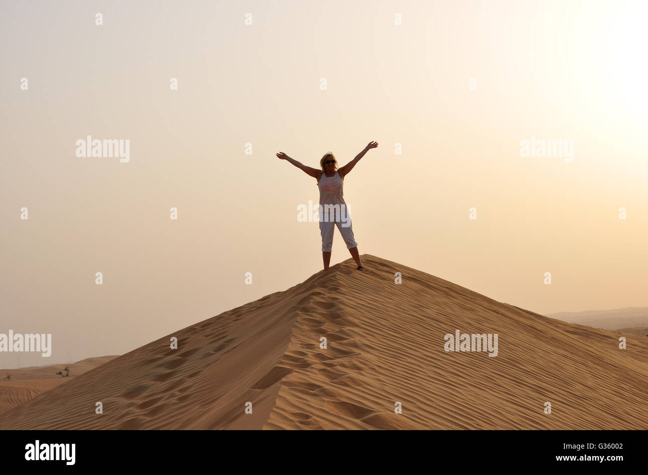 Mädchen, Person, Frau auf der Sanddüne Hallo winken. Auf Wiedersehen, Dubai VAE, Sonnenuntergang oder in der Sonne steigen, Cool der Wüste. Silhouette in der Wüste Stockfoto