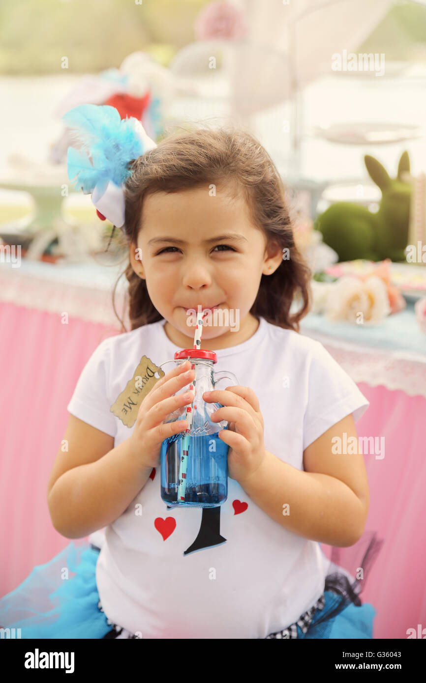 Niedliche Mädchen trinken die "Trink mich" Trank, Alice im Wunderland Tee-Party Thema Muskelaufbau Stockfoto