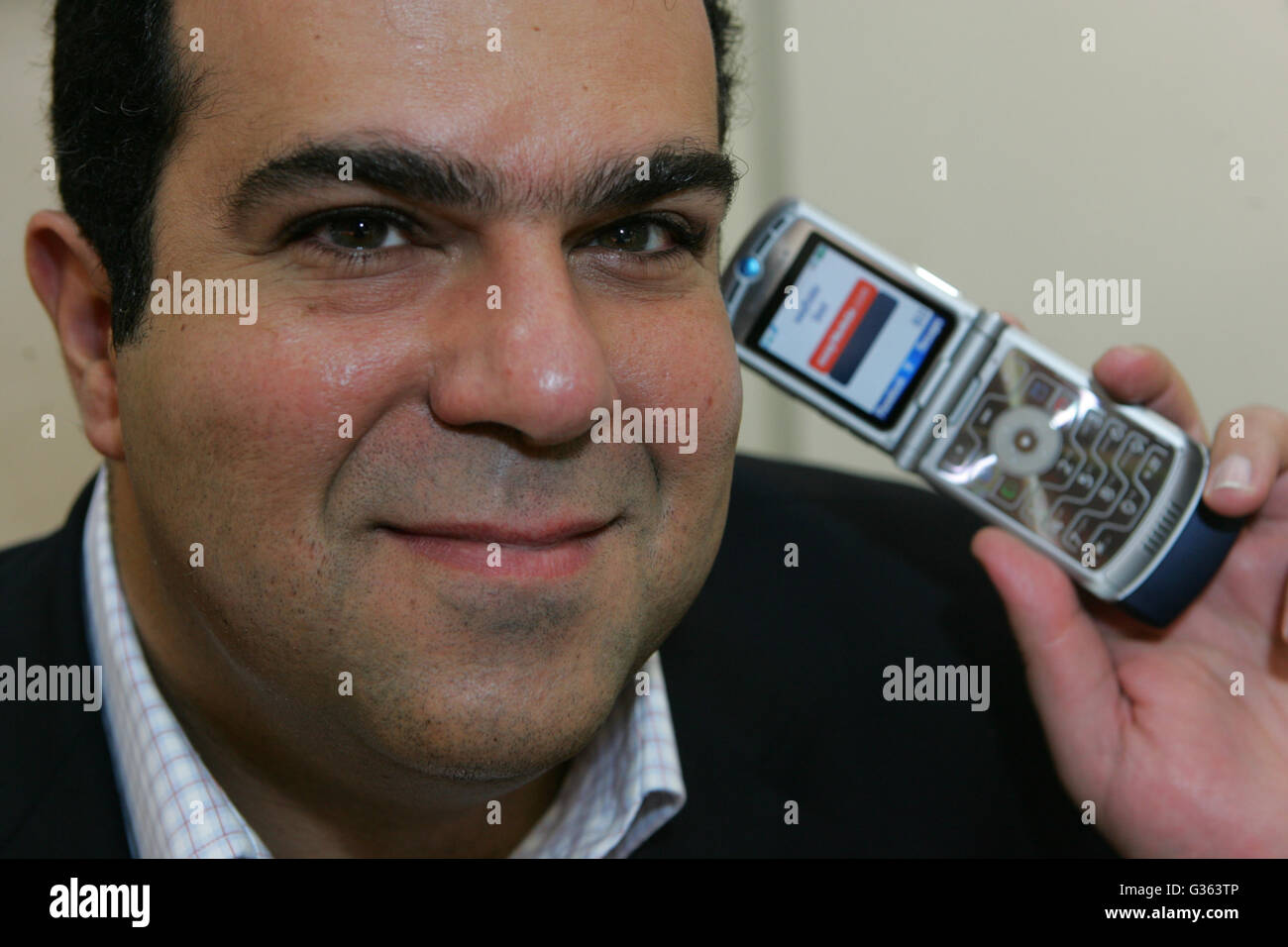 Business Tycoon stellt Stelios mit einem Mobiltelefon Stockfoto