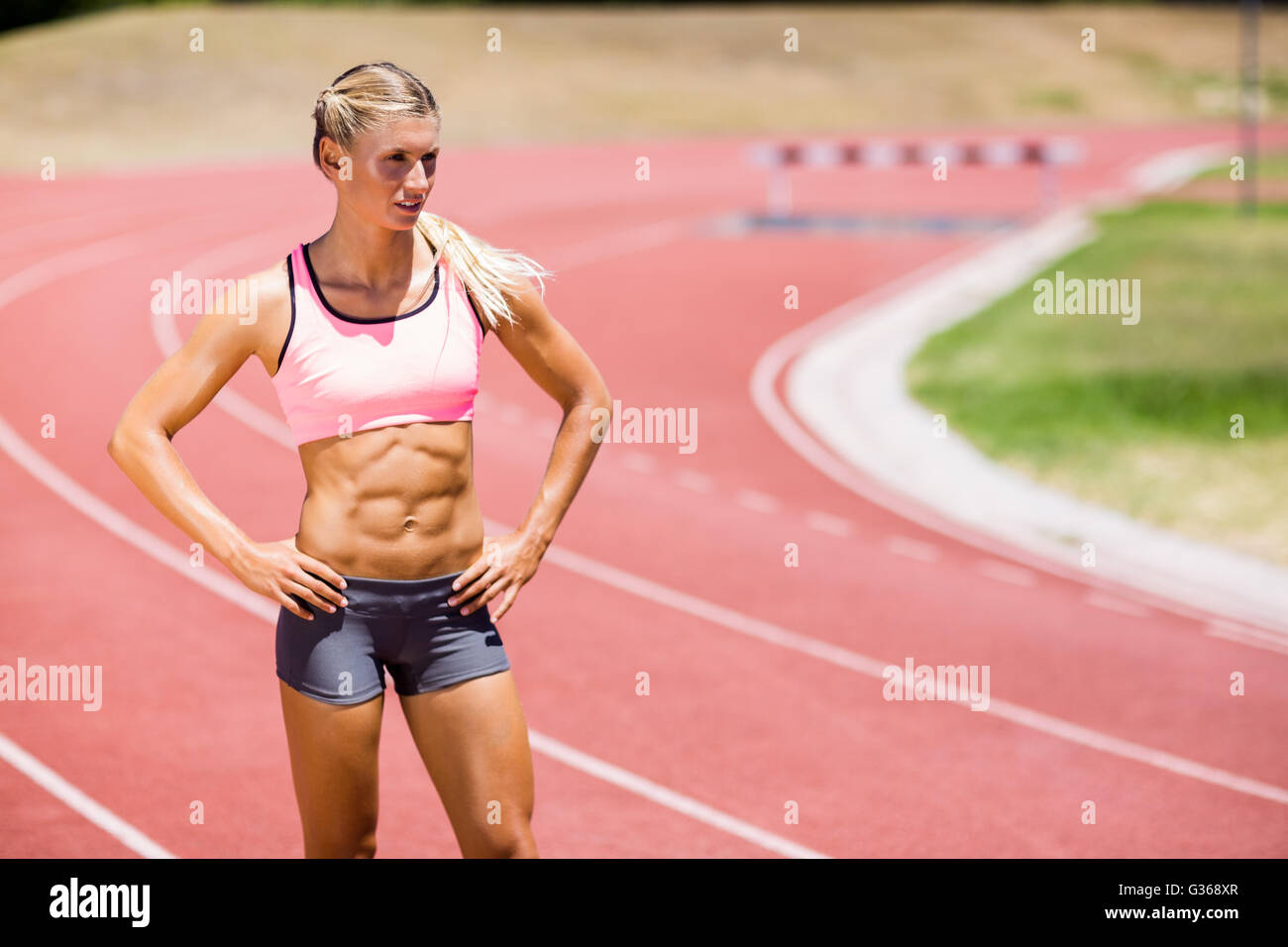 Sportlerin stehend mit der Hand auf den Hüften auf der Laufstrecke Stockfoto