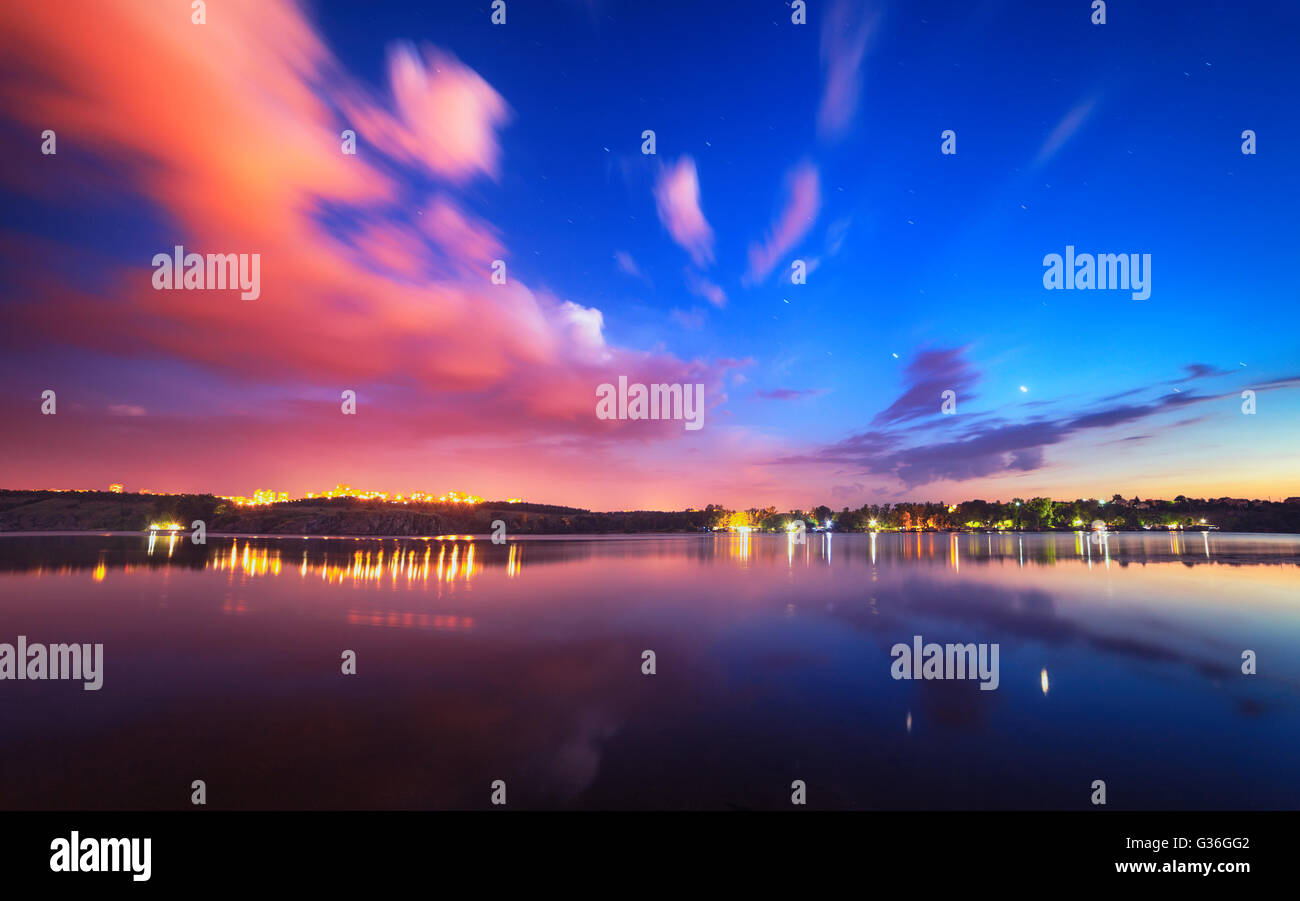Bunte Nacht-Landschaft am See mit blauen Himmel und ziehenden Wolken spiegeln sich in Wasser. Natur-Hintergrund Stockfoto Bunte Nacht-Landschaft am See mit blauen Himmel und ziehenden Wolken spiegeln sich in Wasser. Natur-Hintergrund Stockfoto