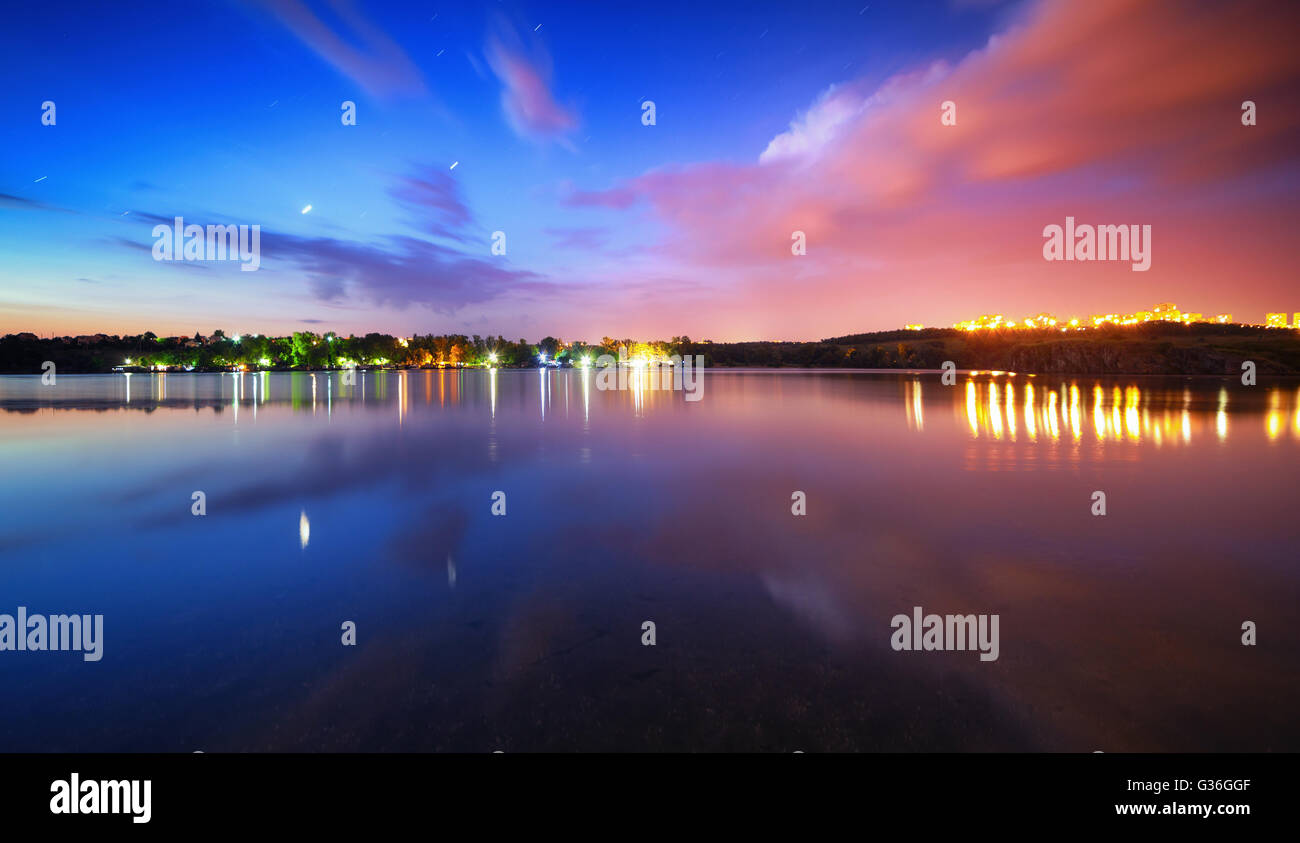 Bunte Nacht-Landschaft am See mit blauen Himmel und ziehenden Wolken spiegeln sich in Wasser. Natur-Hintergrund Stockfoto