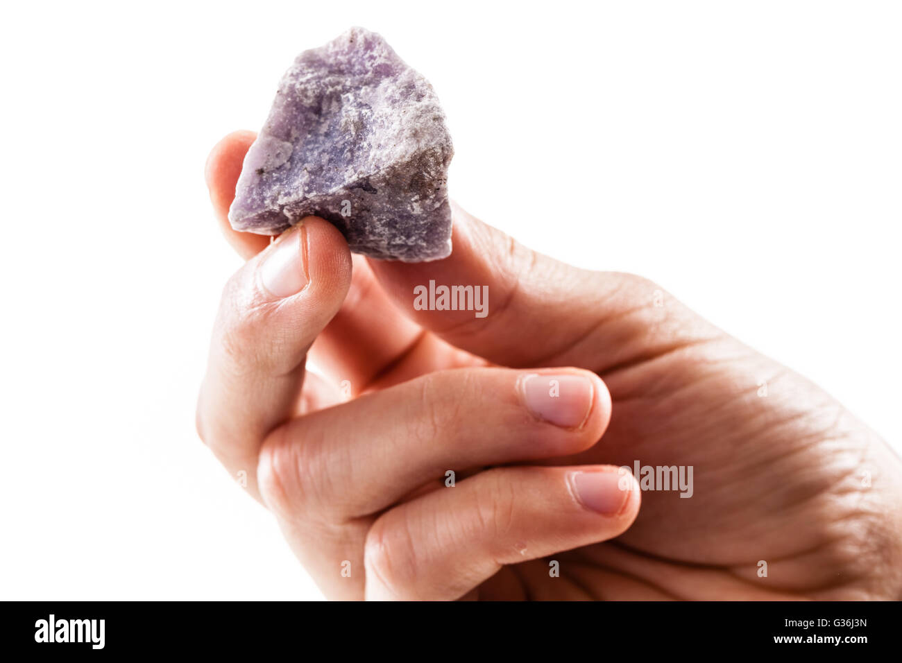 eine männliche Hand, die ein Fragment der Lepidolith Mineral isoliert auf weißem Hintergrund Stockfoto