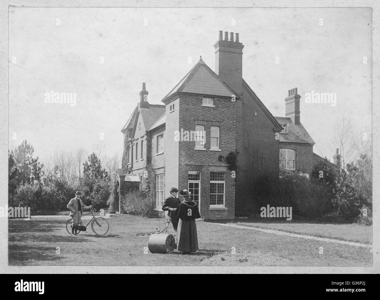 Thomas Hardy, britischer Schriftsteller und Dichter, im Garten seines Hauses am Max Gate in Dorchester, Dorset.  Hardy entworfen, das Haus und sein Bruder baute es--Hardy und seine erste Frau Emma zog es im Jahr 1885.  Er kann hier mit seinem Fahrrad gesehen.      DAT Stockfoto