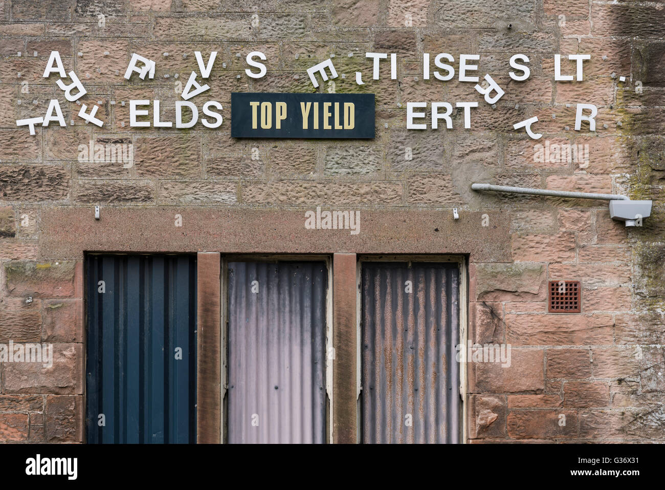 Fehlende Buchstaben machen ein Geheimnis-Zeichen auf einem stillgelegten landwirtschaftlichen Händler Laden in Wooler, Northumberland, UK Stockfoto