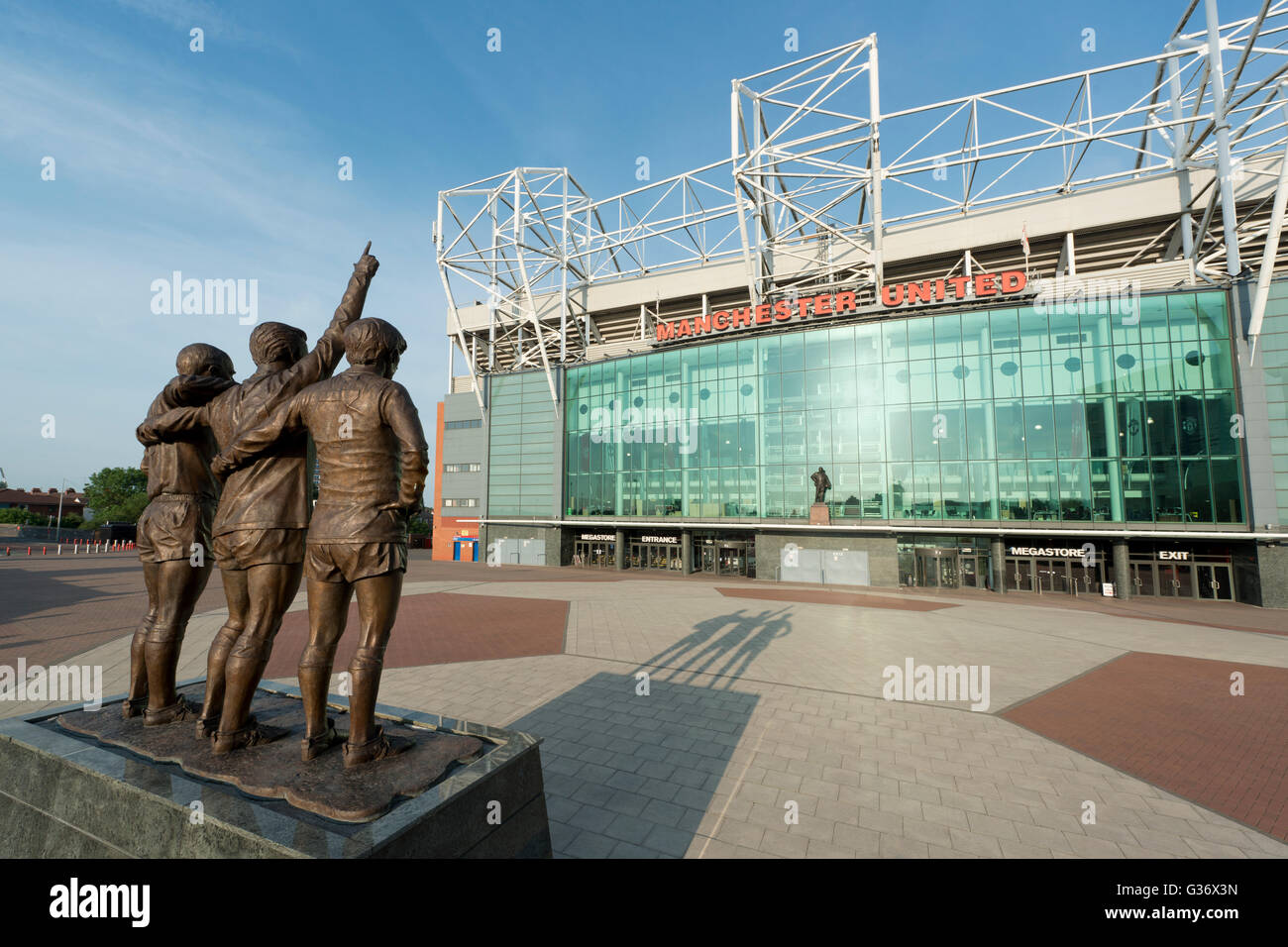 Old Trafford, das Stadion von Manchester United Football Club, mit der Trinity United-Statue an einem sonnigen Tag (nur zur redaktionellen Verwendung) Stockfoto
