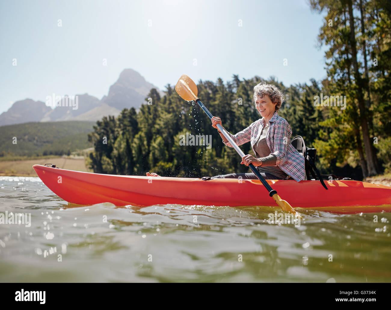Schuss von senior Frau Kajak auf See an einem Sommertag. Reife Frau eine Kajak in See paddeln. Stockfoto