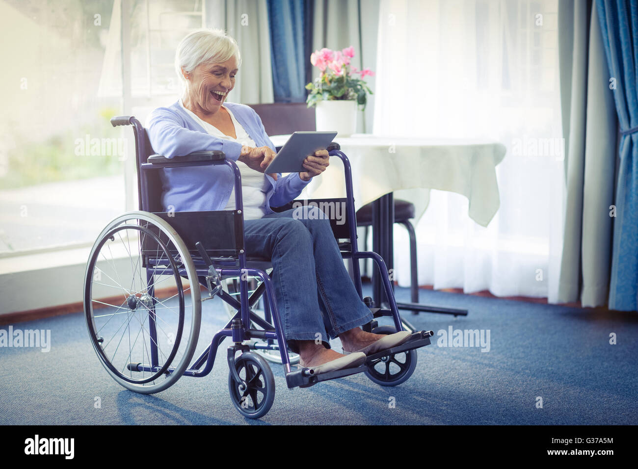 Aufgeregt senior Frau im Rollstuhl mit digital-Tablette Stockfoto