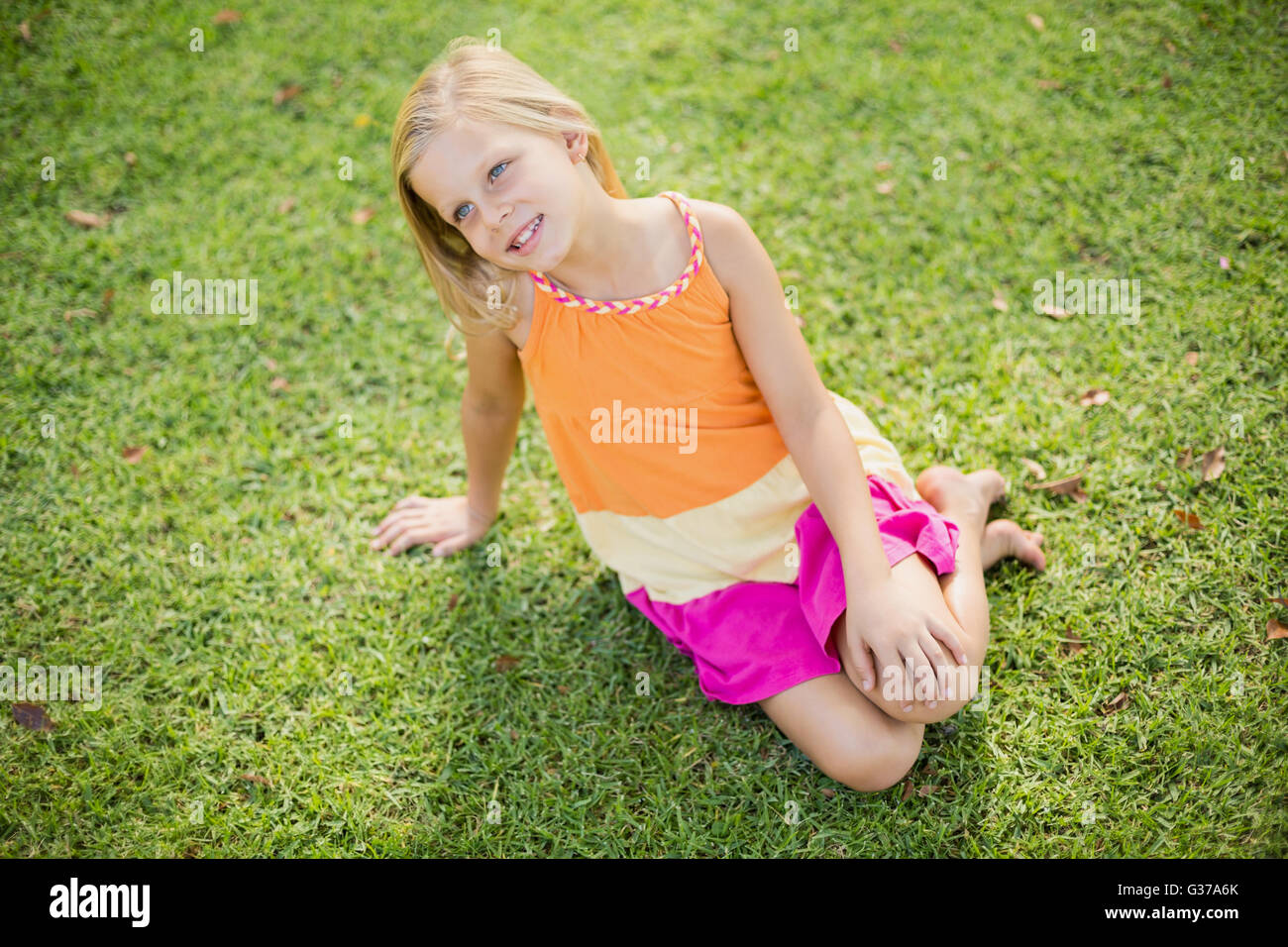 Junges Mädchen sitzen auf dem Rasen Stockfoto