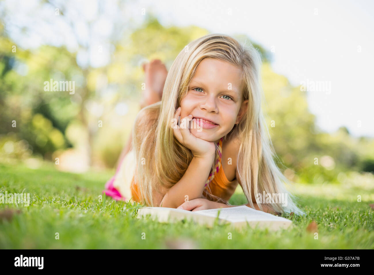 Junges Mädchen auf dem Rasen liegend mit Buch Stockfoto