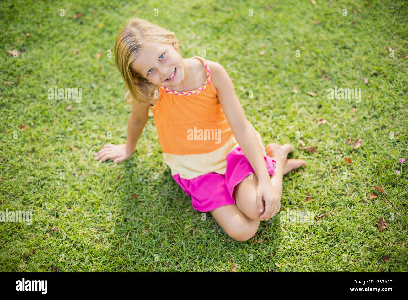 Junges Mädchen sitzen auf dem Rasen Stockfoto