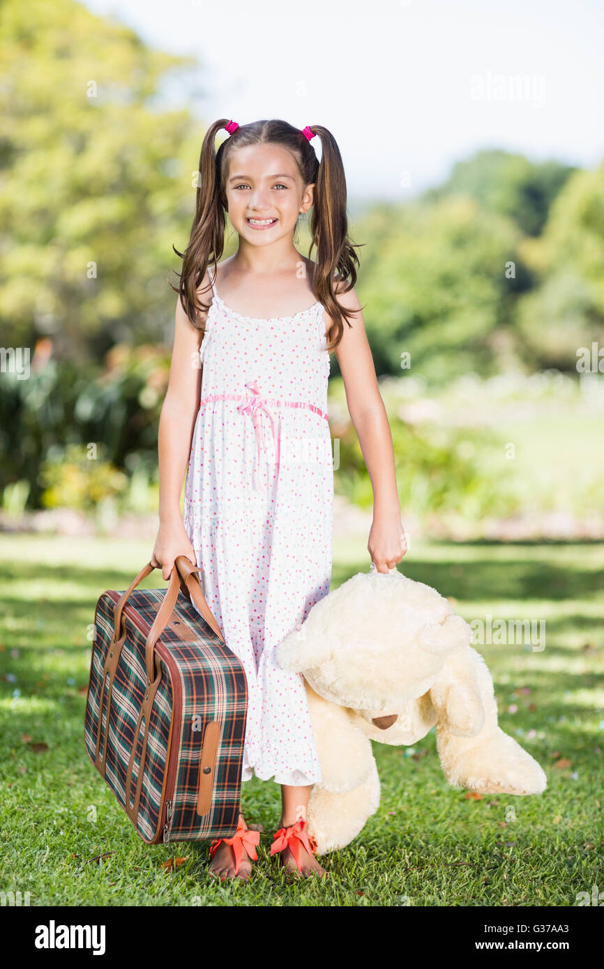Junges Mädchen hält einen Koffer und Teddybär Stockfoto