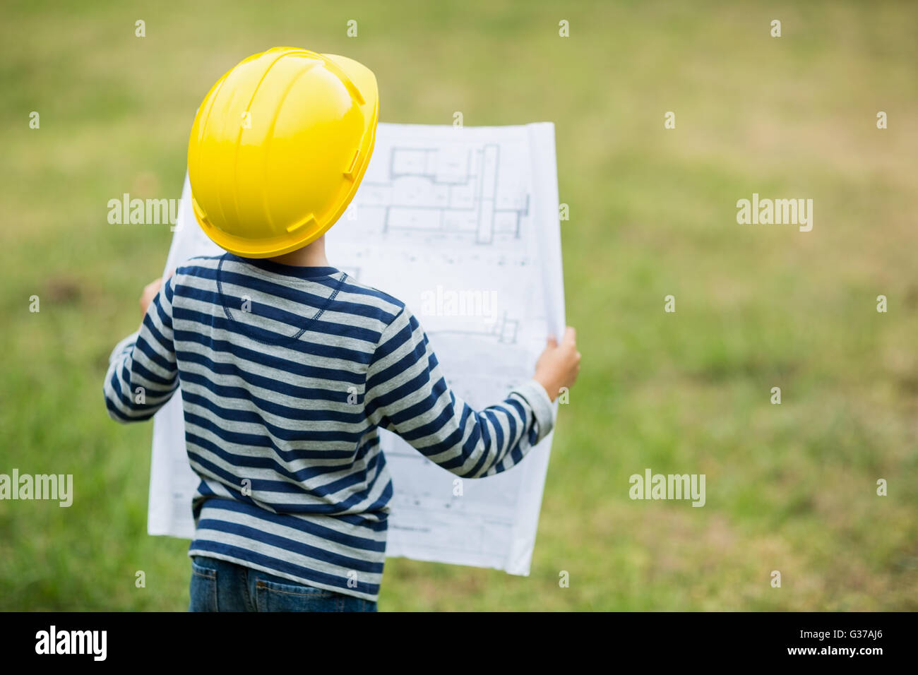 Junge im harten Hut, einen Plan zu lesen Stockfoto