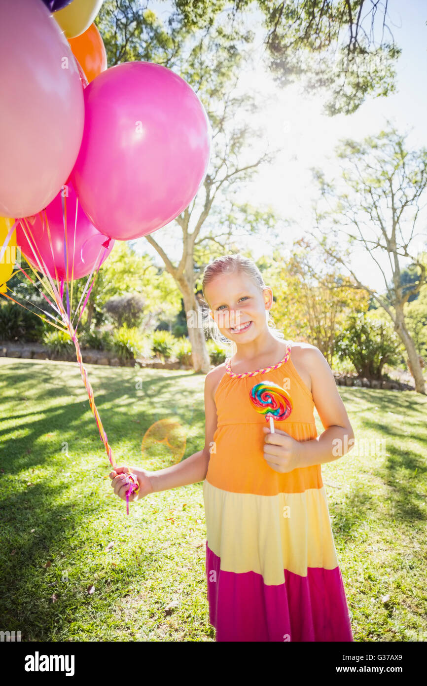 Porträt von lächelndes Mädchen mit Luftballons und Lutscher im park Stockfoto