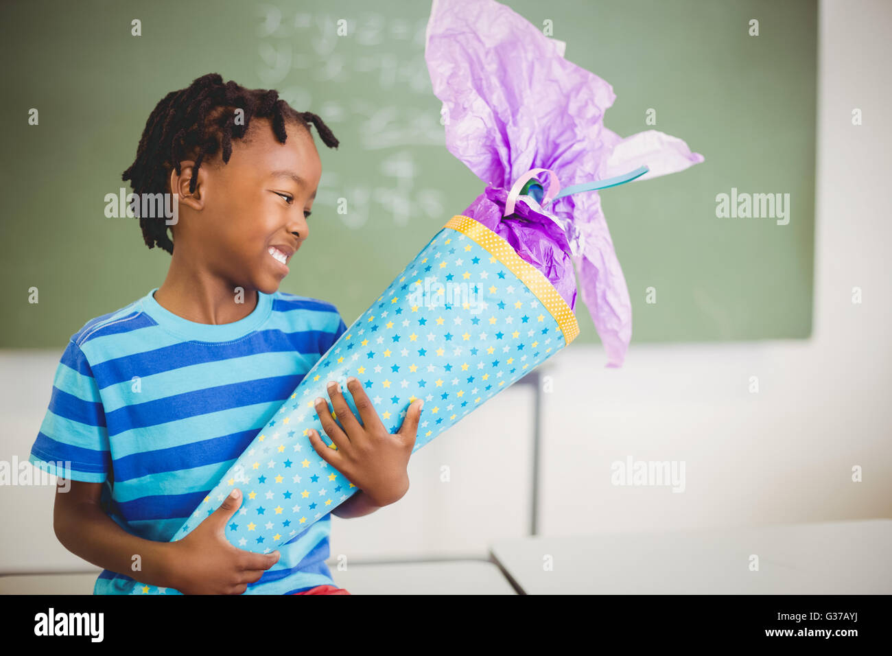 Glückliche Schüler halten Geschenk im Klassenzimmer Stockfoto