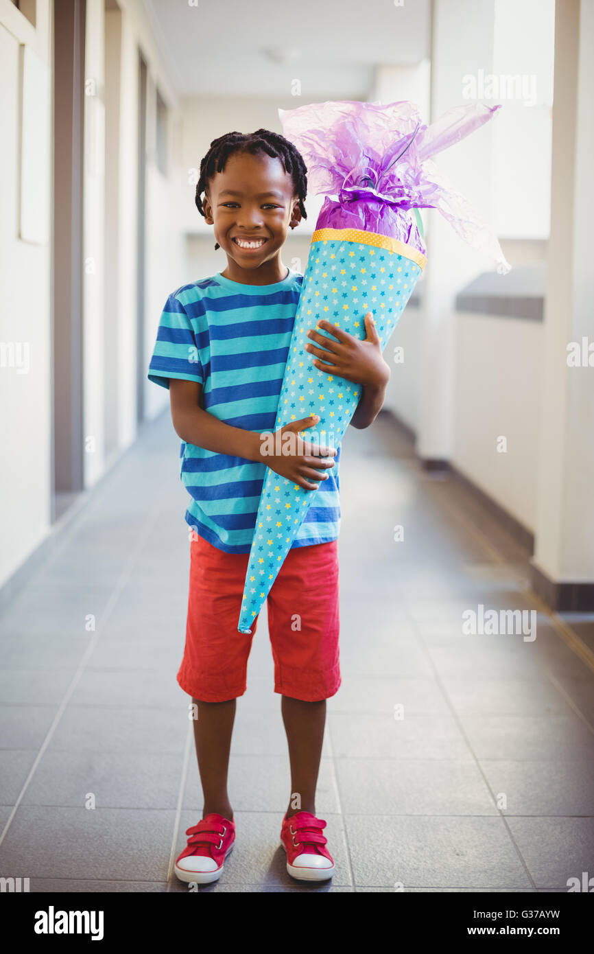Porträt des Lächelns Schuljunge Holding Geschenk im Korridor Stockfoto