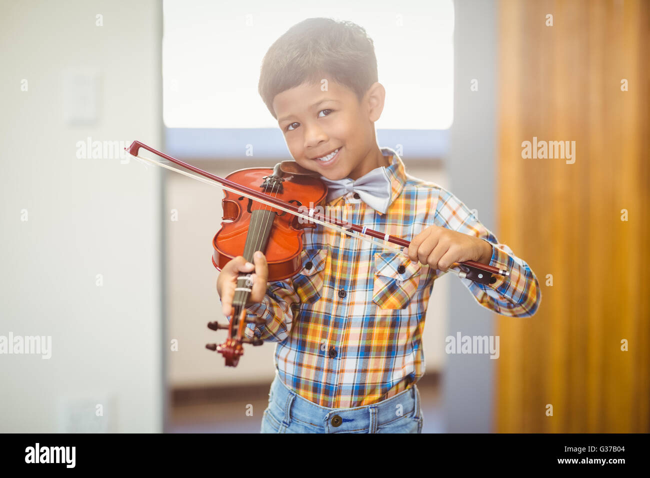 Porträt von lächelnden Schuljunge Geigenspiel im Klassenzimmer Stockfoto