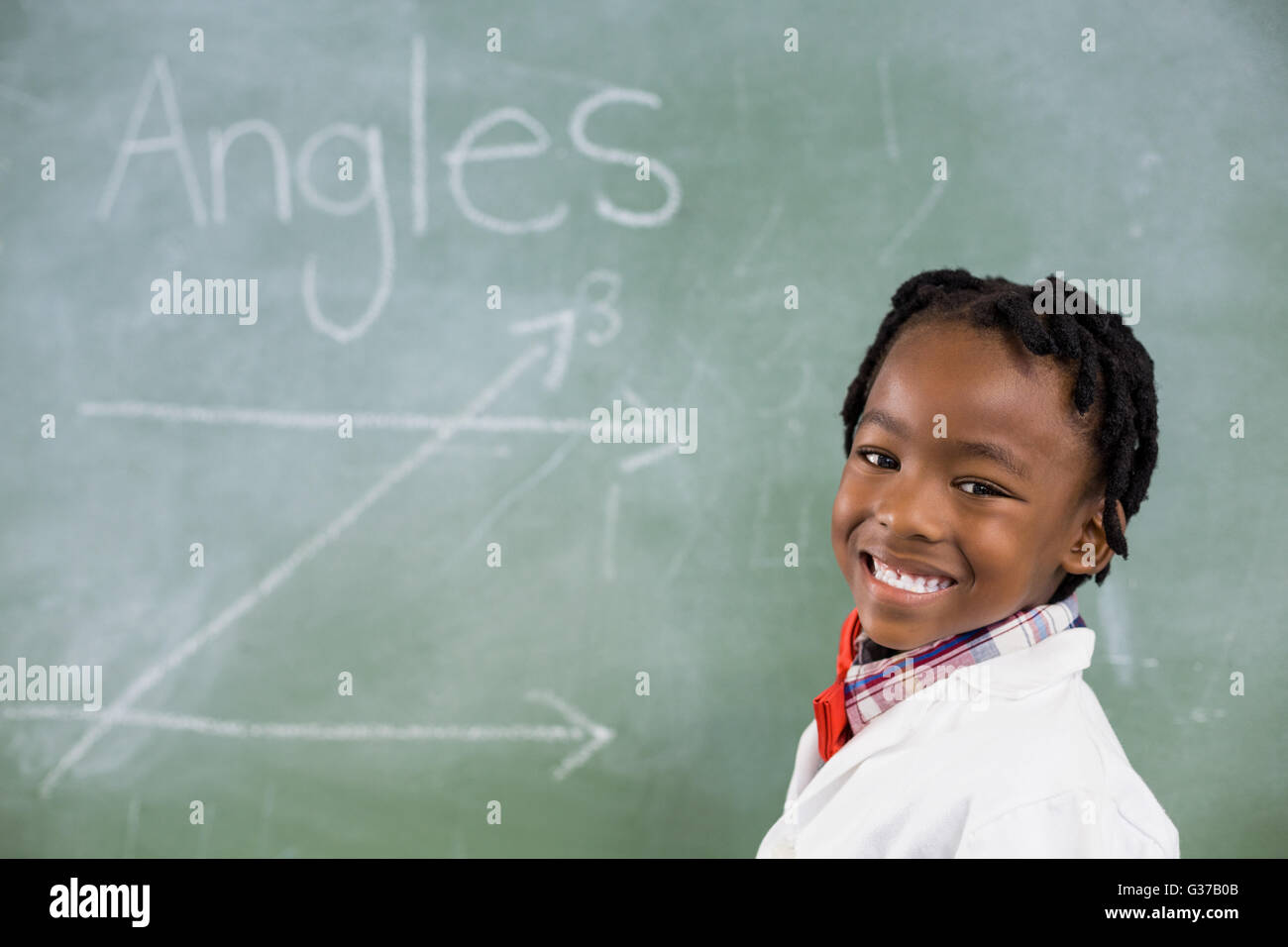 Porträt von Schuljunge lächelnd gegen Tafel im Klassenzimmer Stockfoto