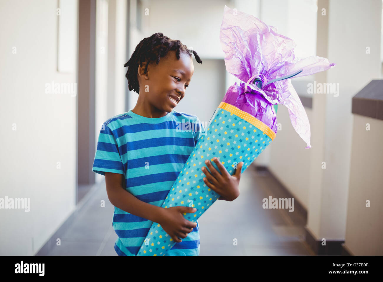 Lächelnde Schuljunge Geschenk in Gang halten Stockfoto