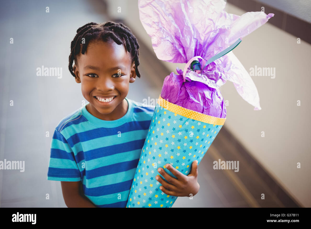 Porträt des Lächelns Schuljunge Holding Geschenk im Korridor Stockfoto